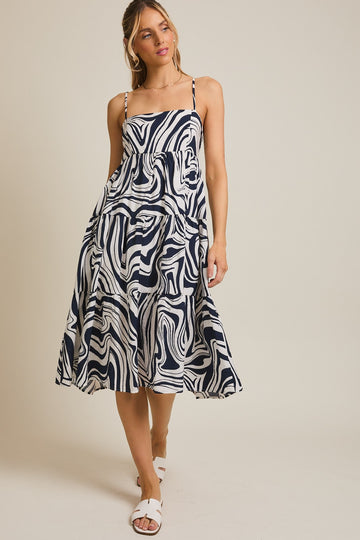 woman wearing a navy and white swirl patterned sundress with spaghetti straps and flowing skirt