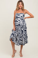 woman wearing a navy and white swirl pattern maternity dress with a tiered skirt and spaghetti straps, showing her baby bump