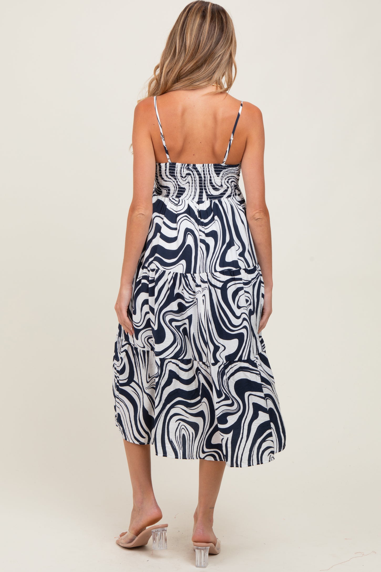 woman wearing a navy and white abstract patterned maternity dress with adjustable straps and tiered skirt