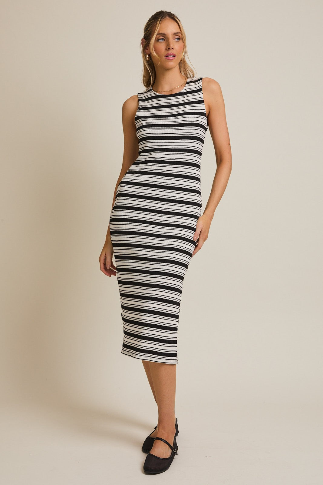 woman wearing a black and white striped midi dress with a fitted silhouette and sleeveless design