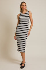 woman wearing a black and white striped midi dress with a fitted silhouette and sleeveless design