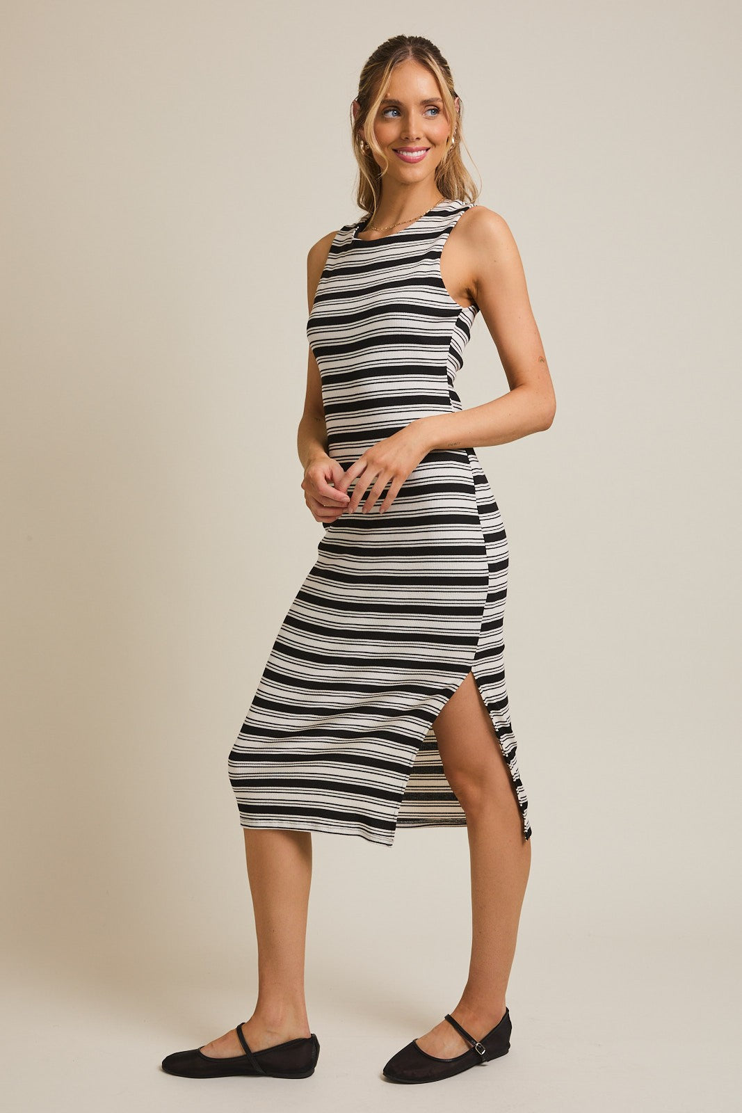 woman wearing a black and white striped midi dress with a side slit and flat shoes