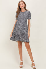 woman wearing a black and white floral print maternity dress with short puff sleeves and a flowy skirt, baby bump visible