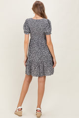 woman wearing a black floral maternity dress with short puff sleeves and a ruffled hem, seen from the back