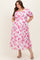 woman wearing a floral pink maternity plus dress with puff sleeves and side pockets