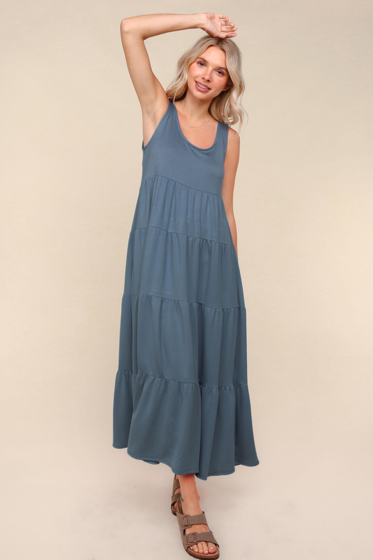 woman wearing a sleeveless teal maxi dress with tiered layers and a relaxed fit
