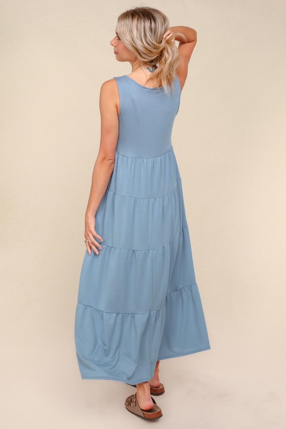 woman wearing a light blue tiered maxi dress with a sleeveless design, showing the back view