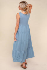 woman wearing a light blue tiered maxi dress with a sleeveless design, showing the back view