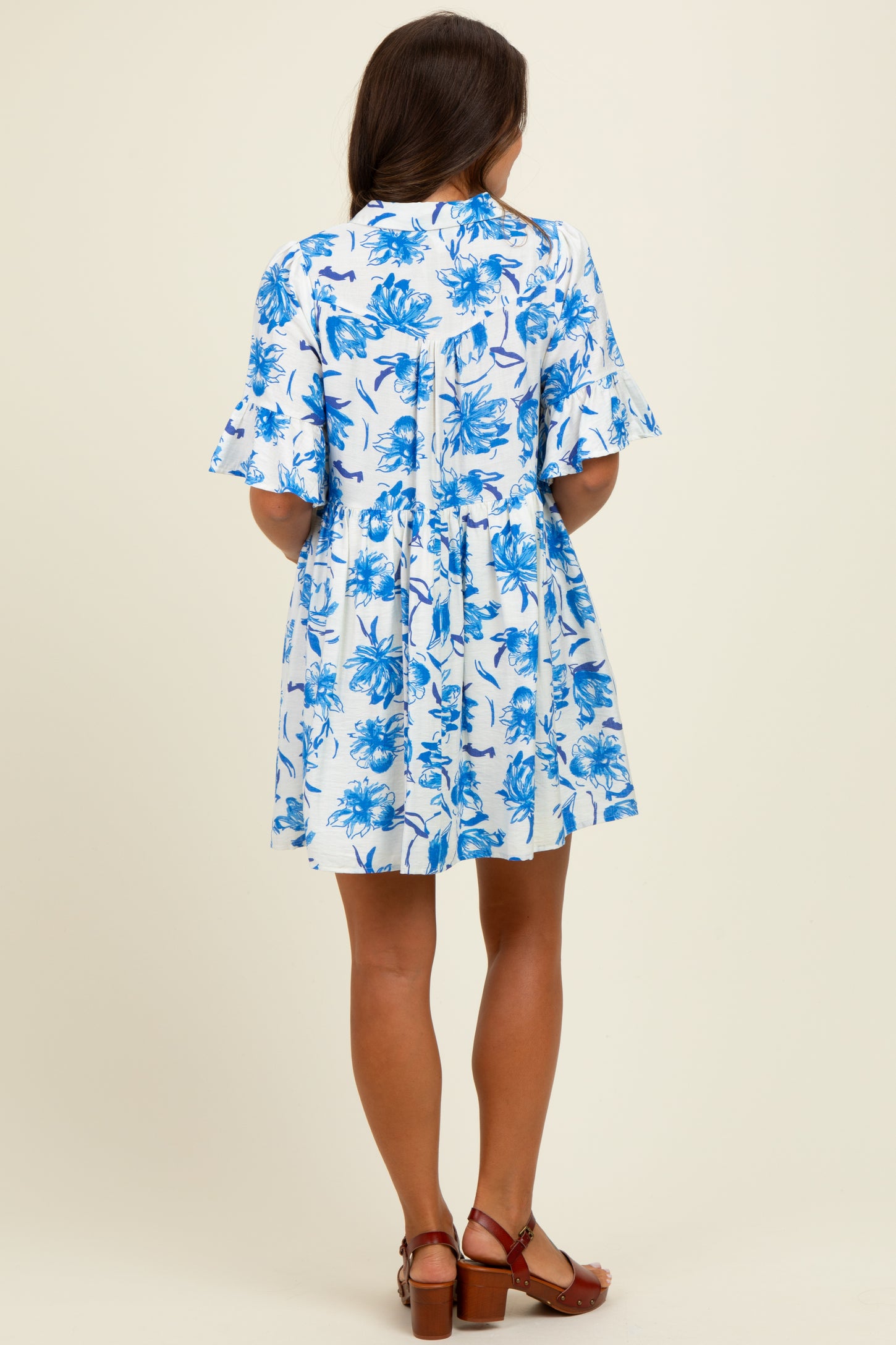 woman wearing a short-sleeve blue and white floral maternity dress, seen from the back
