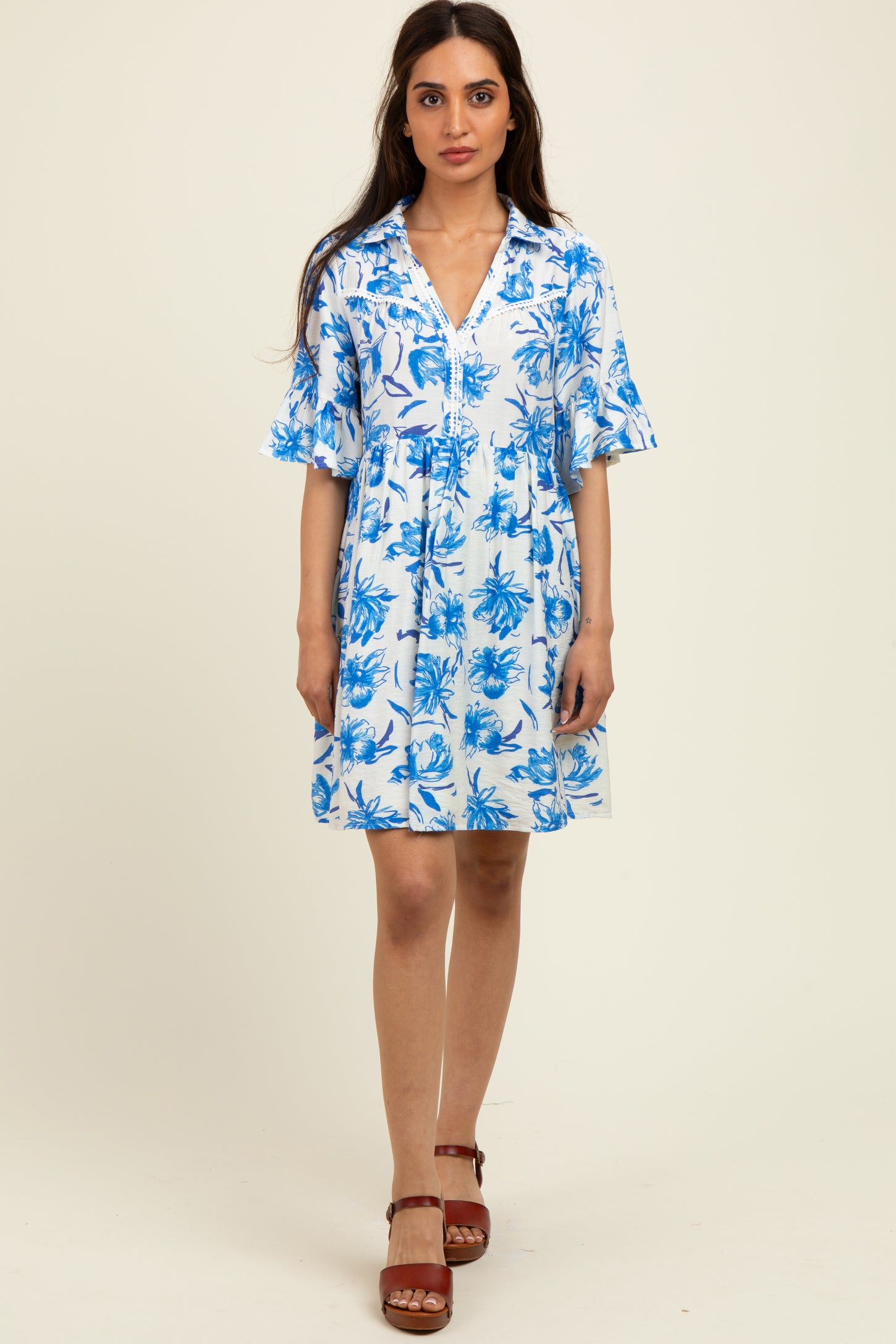 woman wearing a blue and white floral short sleeve collared dress with a fitted bodice and flared skirt