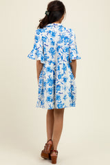 woman wearing a blue and white floral short sleeve dress with a loose fit and flared sleeves, standing with her back to the camera