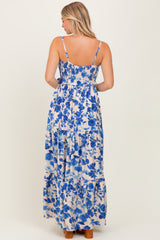 woman wearing a blue and white floral maxi dress with spaghetti straps, showcasing a smocked bodice and tiered skirt.