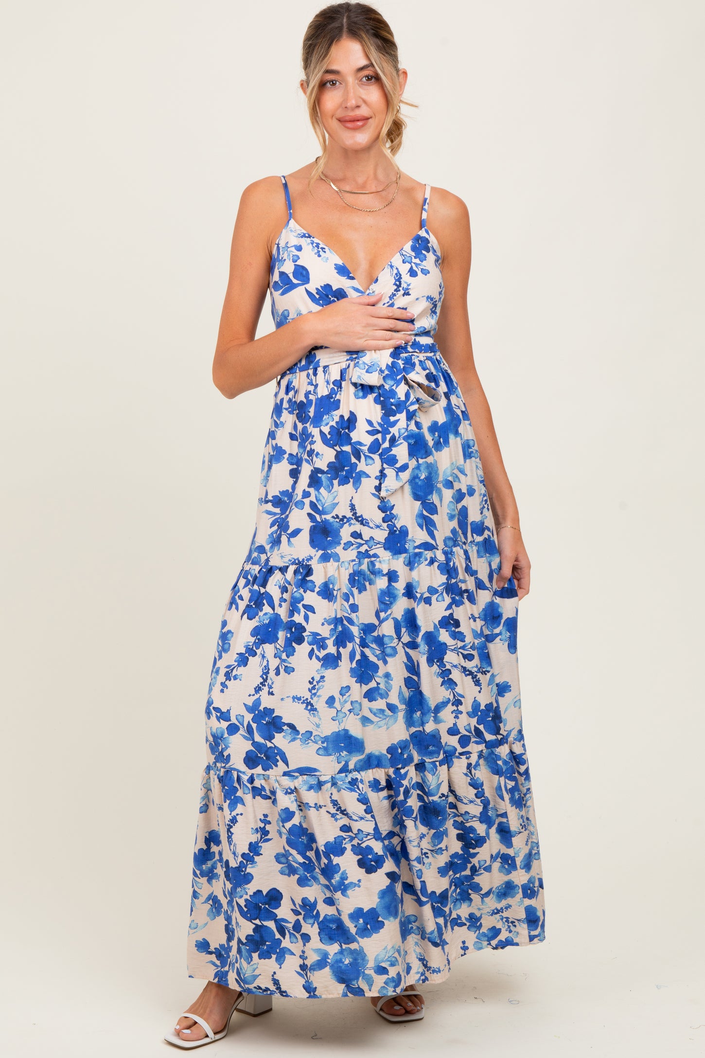 woman wearing a floral blue and white maxi maternity dress with adjustable straps and tiered bottom, showing baby bump