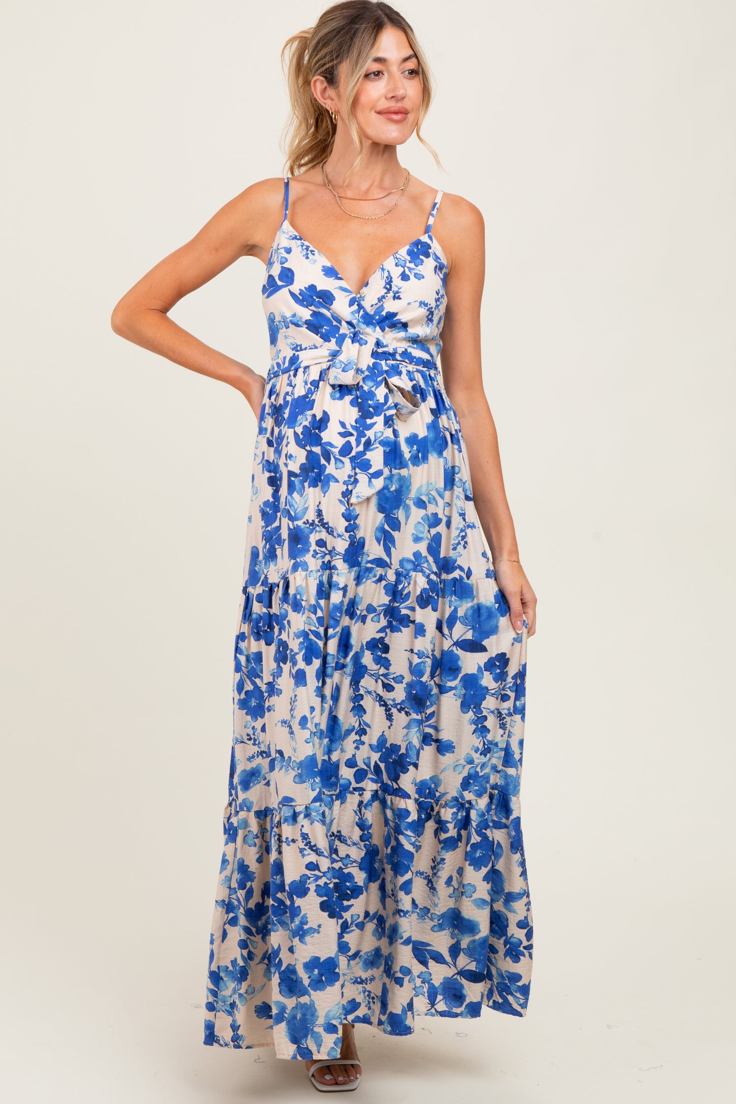 woman wearing a blue floral print maternity maxi dress with a cinched waist and adjustable straps