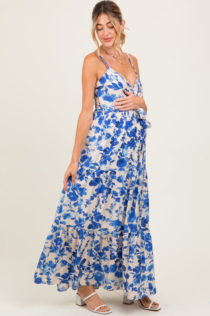 woman wearing a floral blue maternity maxi dress with spaghetti straps and tiered hem, highlighting her baby bump