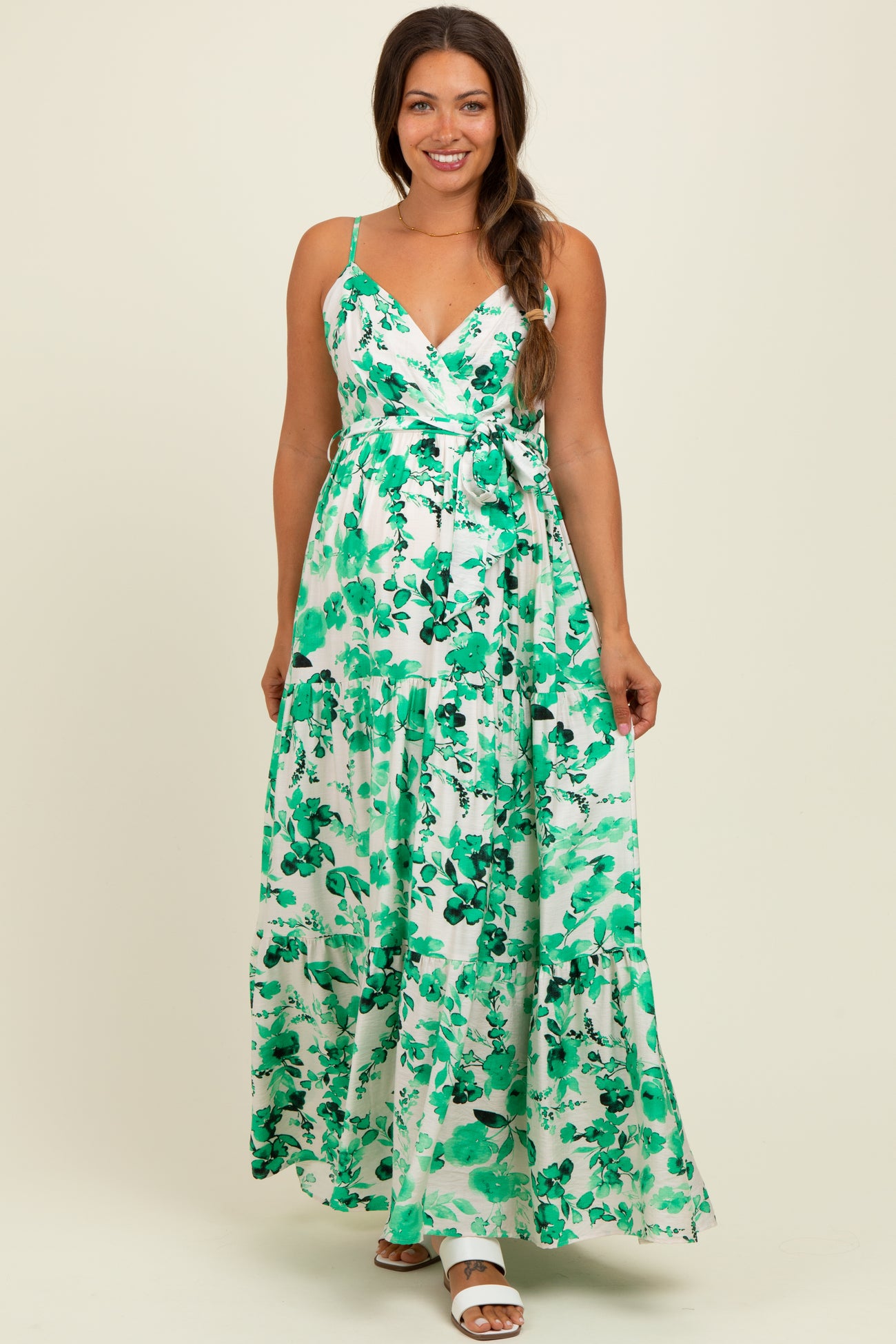 woman wearing a green and white floral maxi maternity dress with adjustable straps and a tie waist