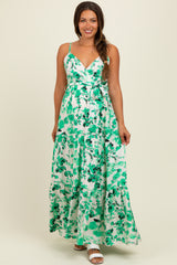 woman wearing a green and white floral maxi maternity dress with adjustable straps and a tie waist