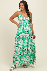 woman wearing a green floral maxi maternity dress with a tie waist and spaghetti straps, showing her baby bump