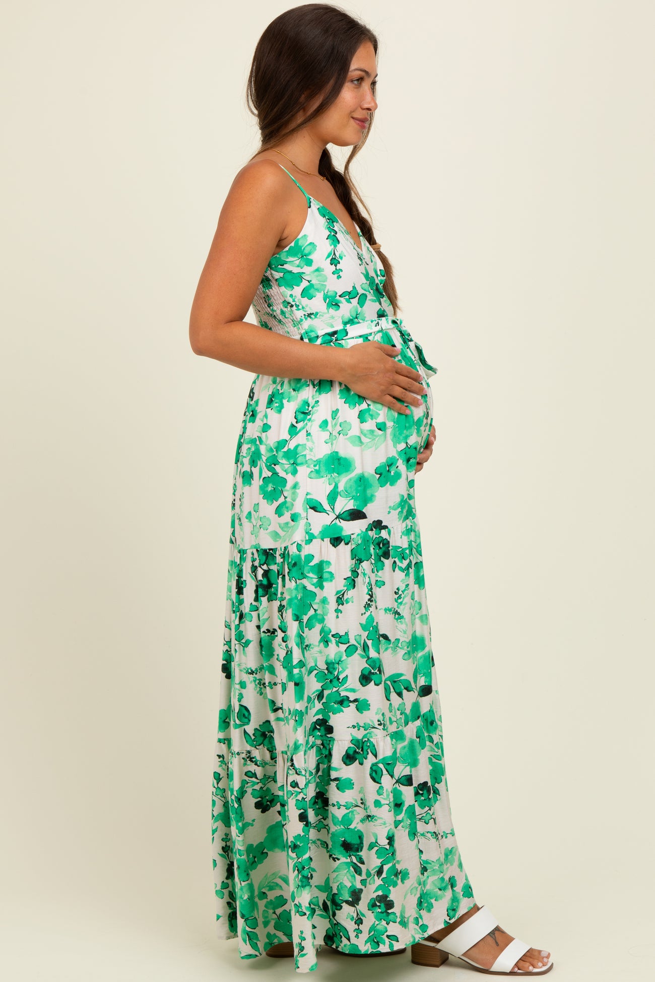 woman wearing a green floral maternity maxi dress and holding her baby bump