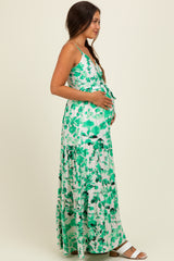 woman wearing a green floral maternity maxi dress and holding her baby bump