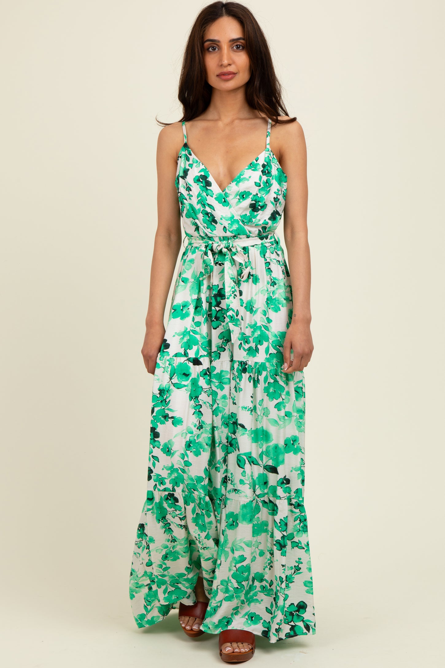 woman wearing a green floral maxi dress with thin straps and a tie waist detail