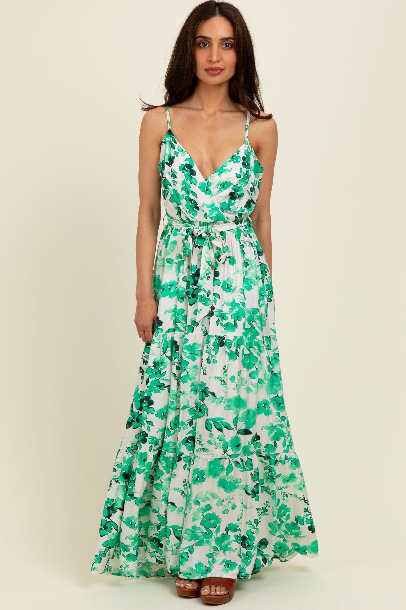 woman wearing a green floral maxi dress with spaghetti straps and a waist tie