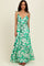 woman wearing a green floral maxi dress with spaghetti straps and a waist tie