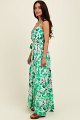 woman wearing a green and white floral maxi dress with a tie waist and spaghetti straps