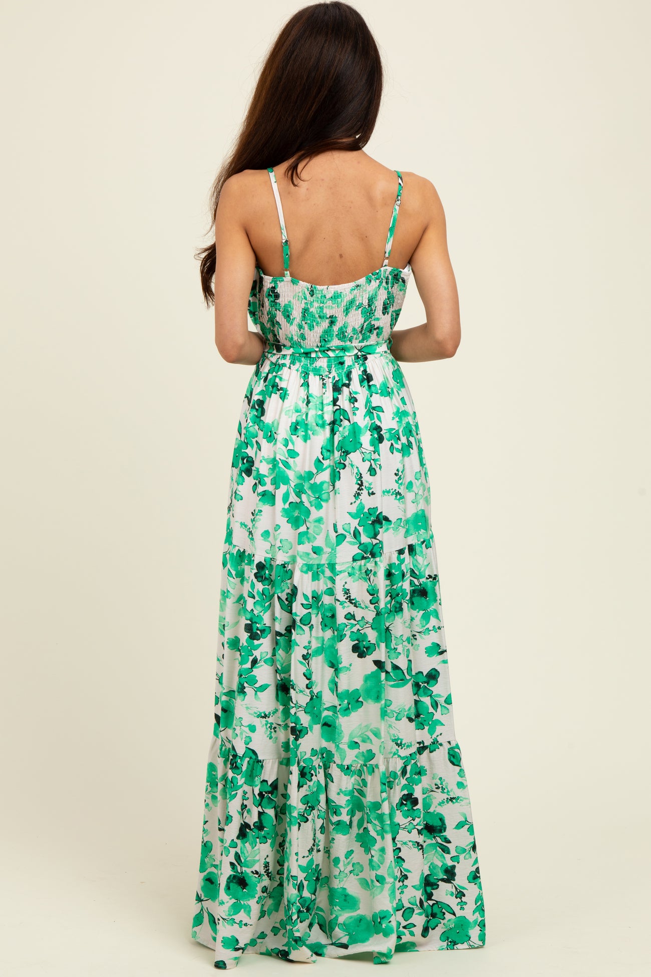 woman wearing a green floral maxi dress with a fitted bodice and flowing skirt, viewed from the back