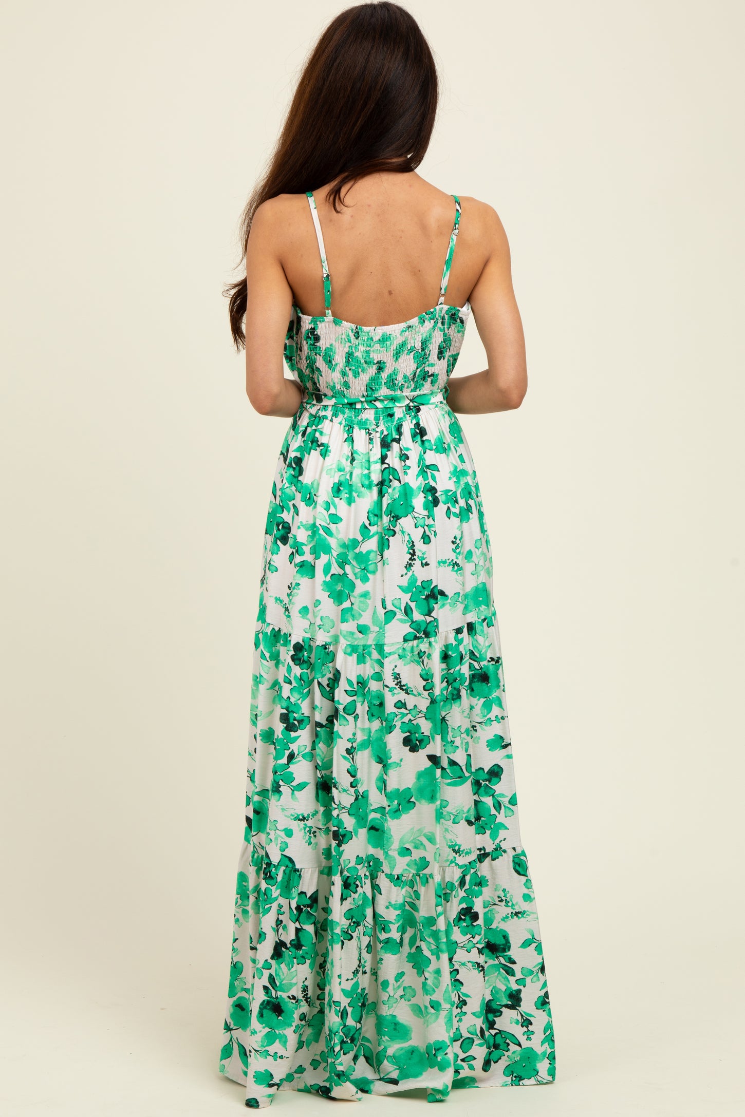 woman wearing a green floral maxi dress with a fitted bodice and flowing skirt, viewed from the back