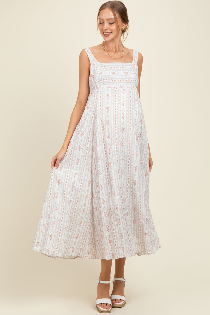 woman wearing a white floral print maternity maxi dress with a square neckline and a visible baby bump