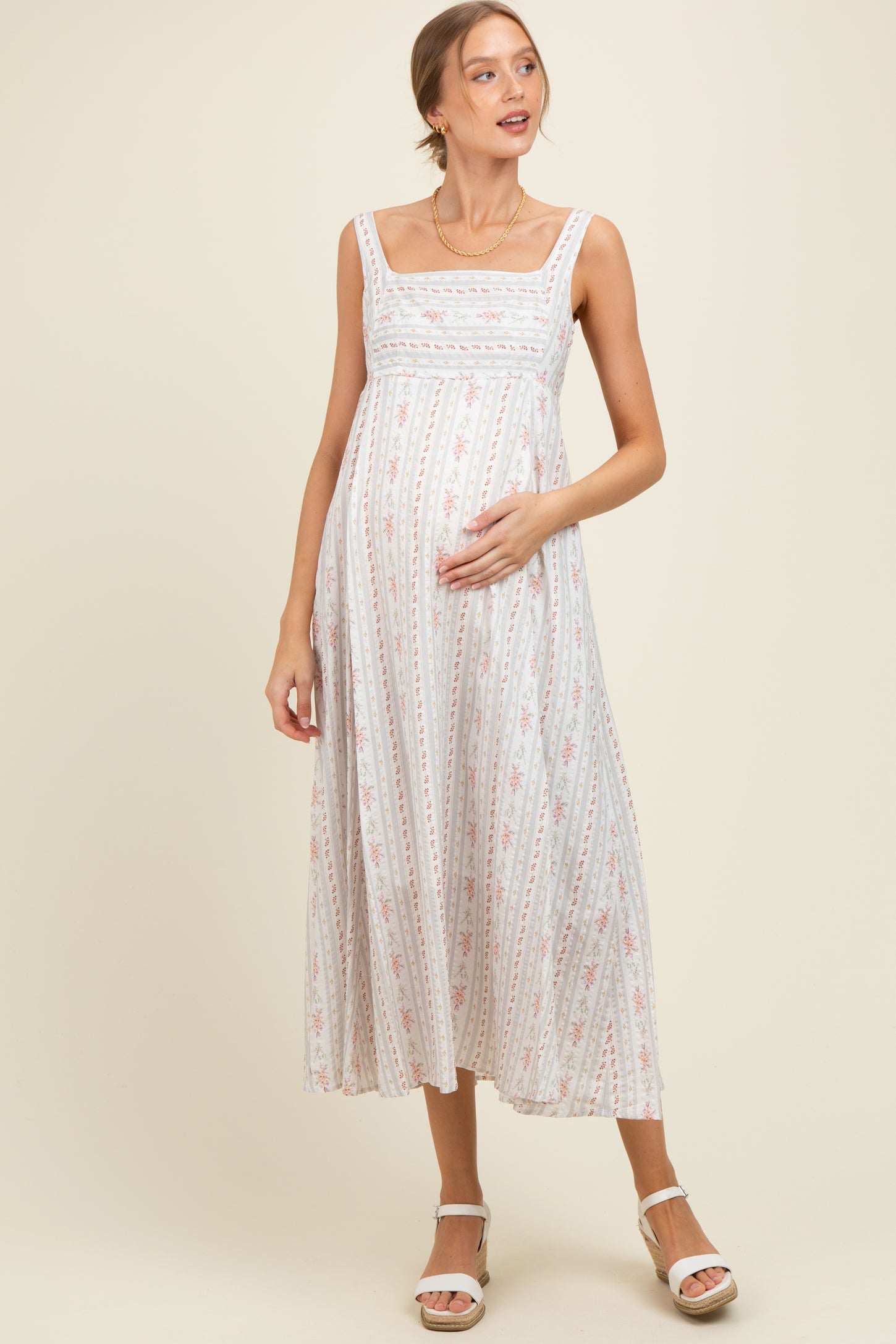woman wearing a light floral print maternity maxi dress and holding her baby bump
