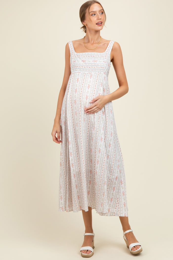 woman wearing a light floral print maternity maxi dress and holding her baby bump