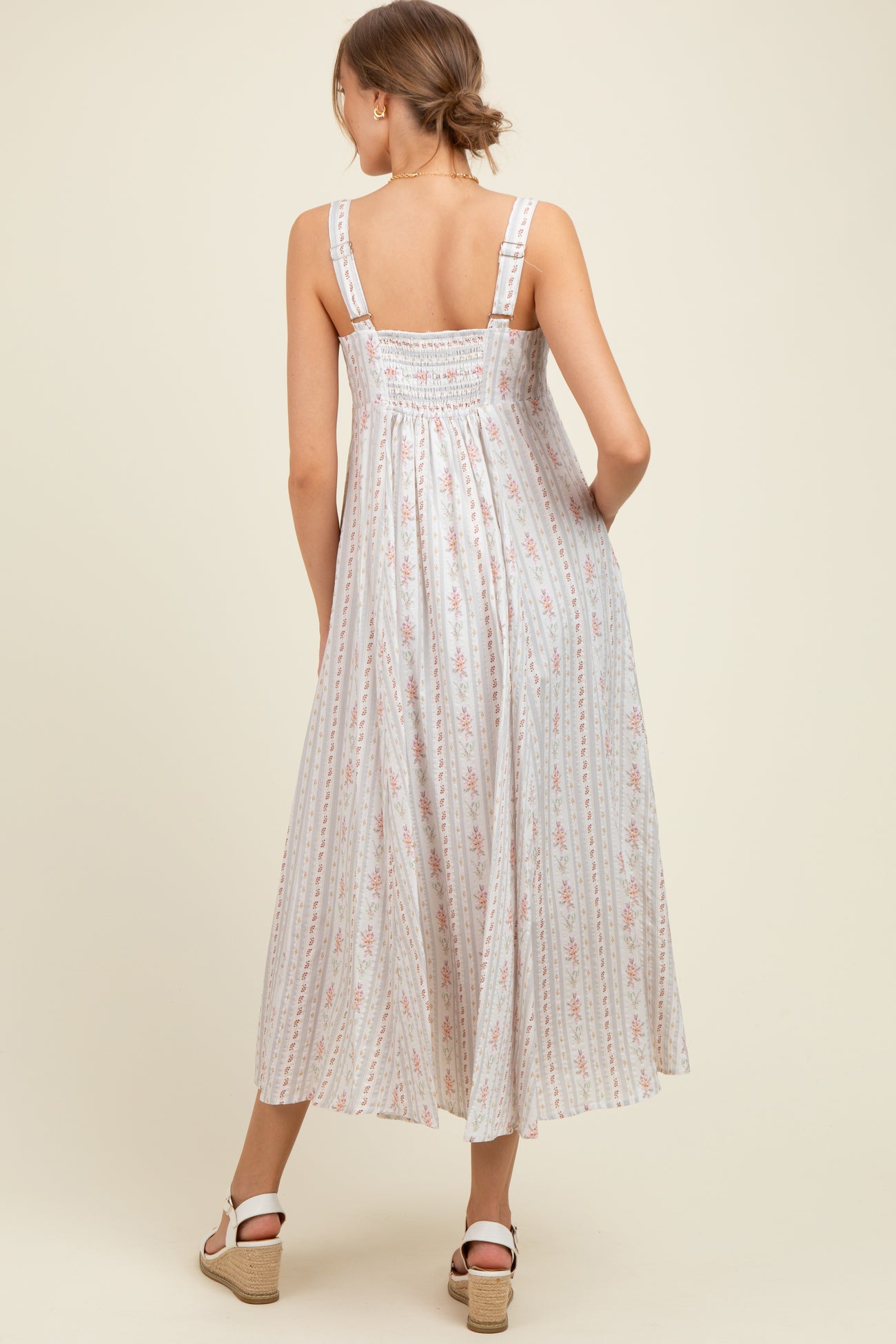 woman wearing a light floral print maternity maxi dress with smocked back and adjustable straps, showing the back view