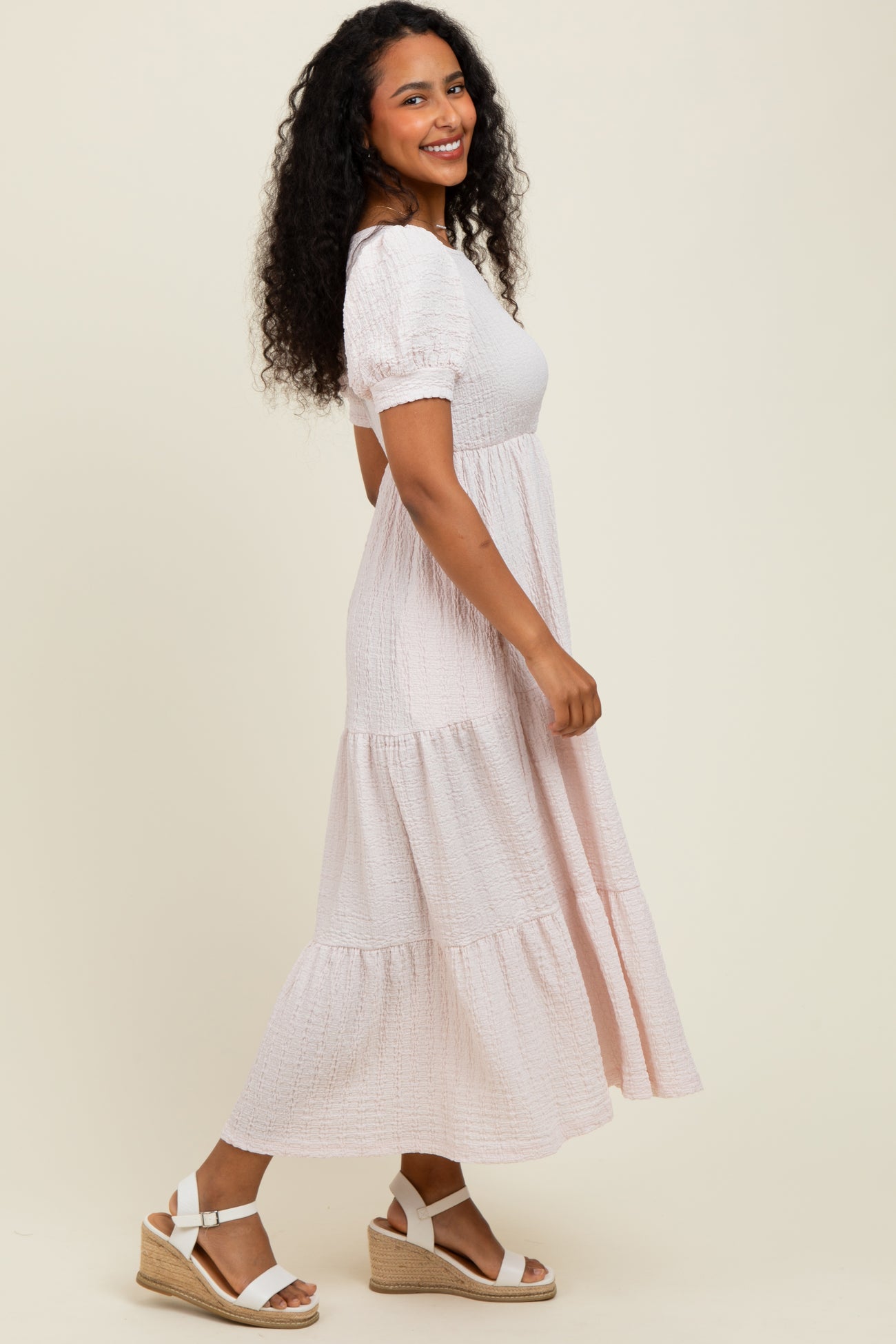 woman wearing a blush pink tiered maxi dress with puff sleeves and white espadrille wedges