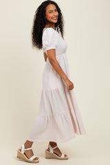 woman wearing a blush pink tiered maxi dress with puff sleeves and white espadrille wedges