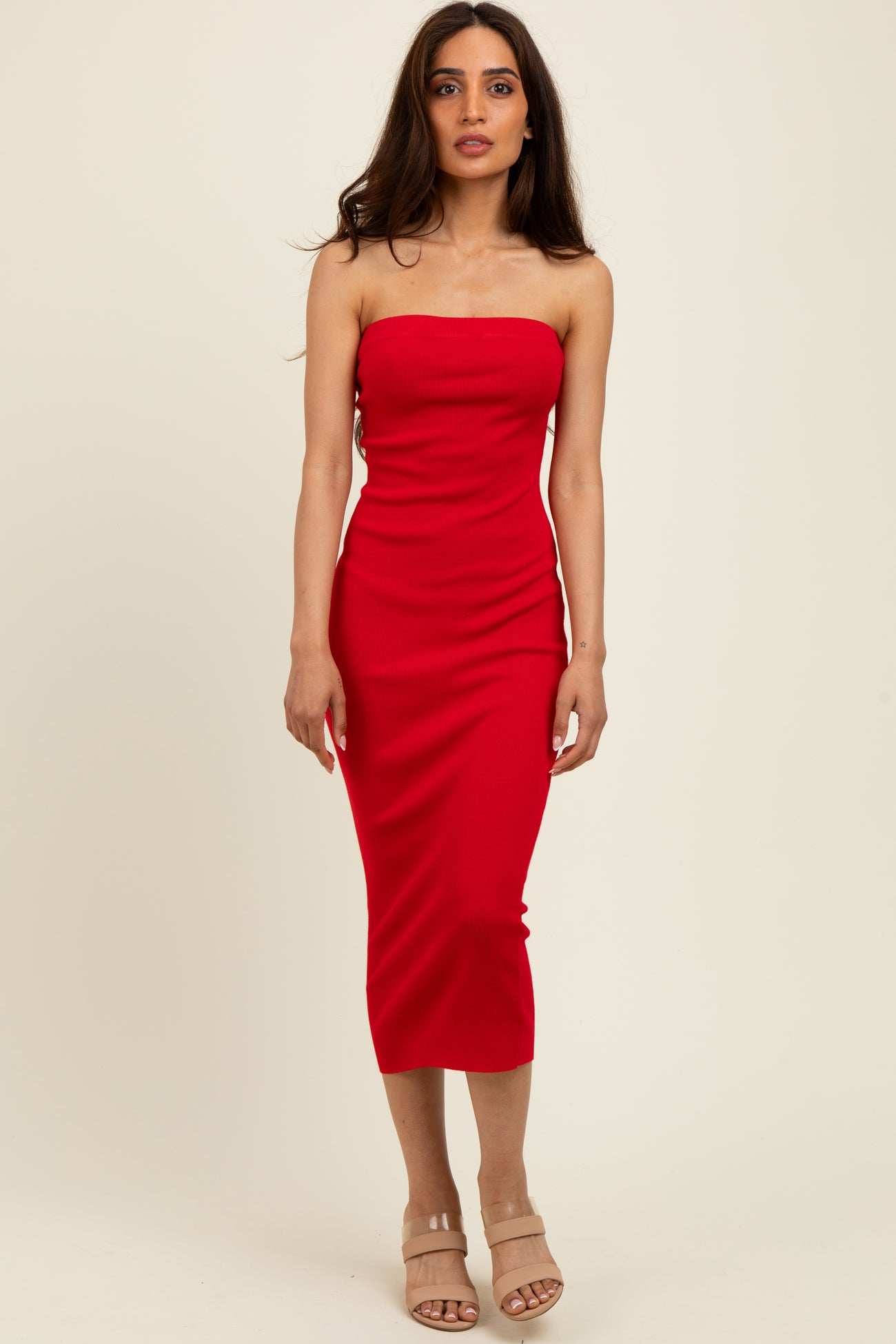 woman wearing a red strapless midi dress with a fitted silhouette and high slit, standing against a neutral background