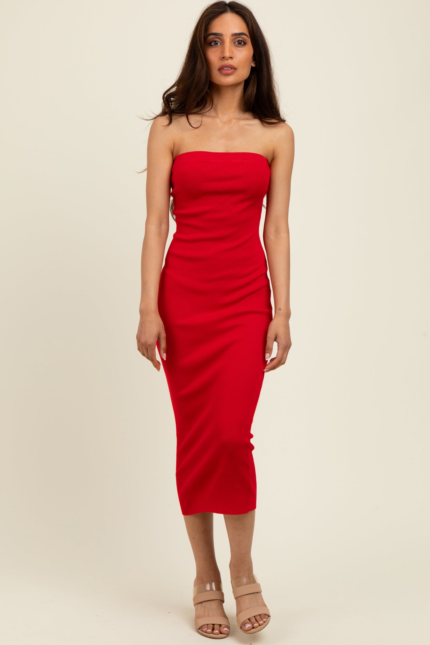 woman wearing a red strapless midi dress with a fitted silhouette and high slit, standing against a neutral background
