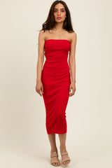woman wearing a red strapless midi dress with a fitted silhouette and high slit, standing against a neutral background