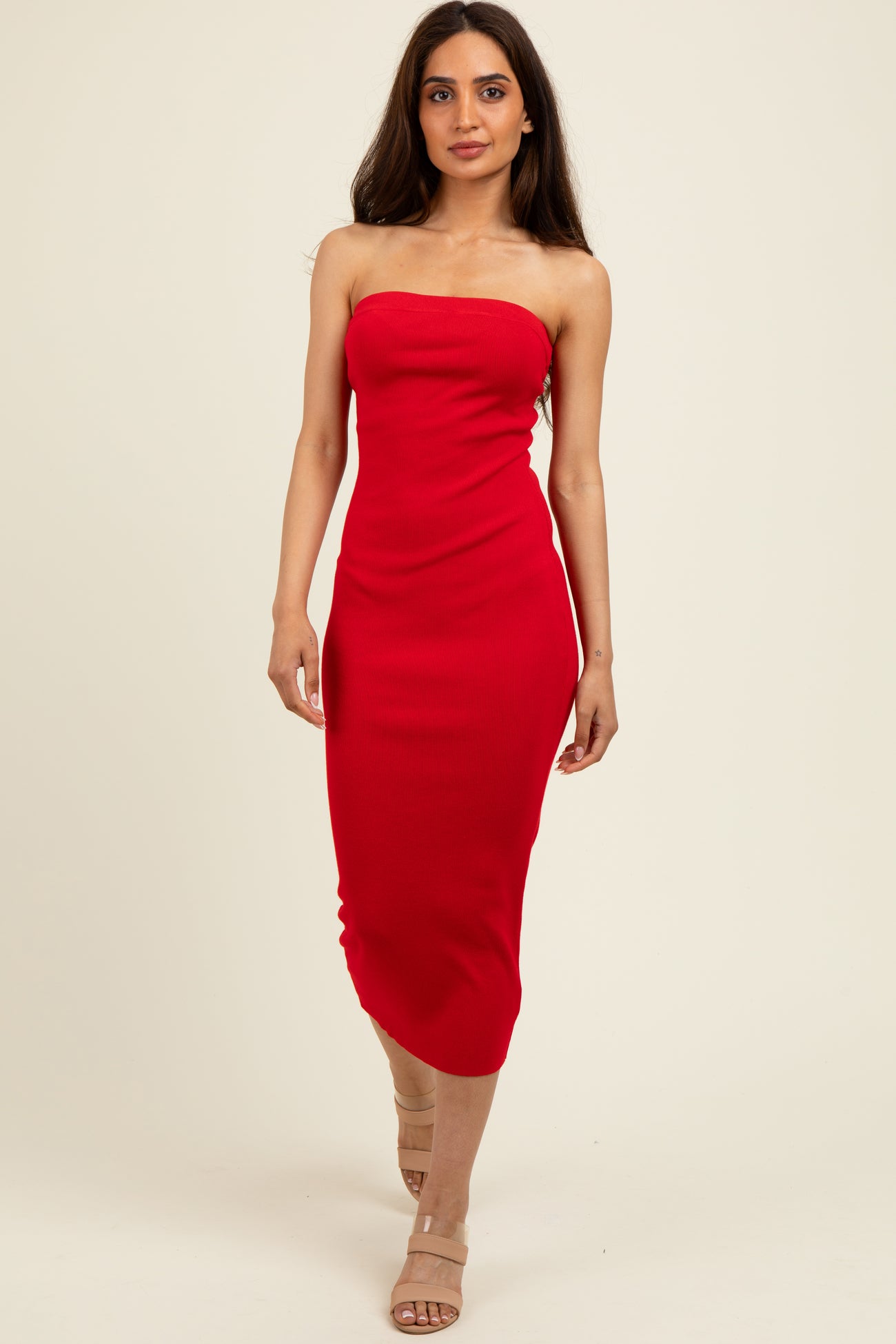 woman wearing a fitted red strapless midi dress with a ribbed texture and paired with nude heels
