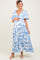 woman wearing a blue and white patterned maternity maxi dress with a v-neck and tiered ruffle sleeves, holding her baby bump