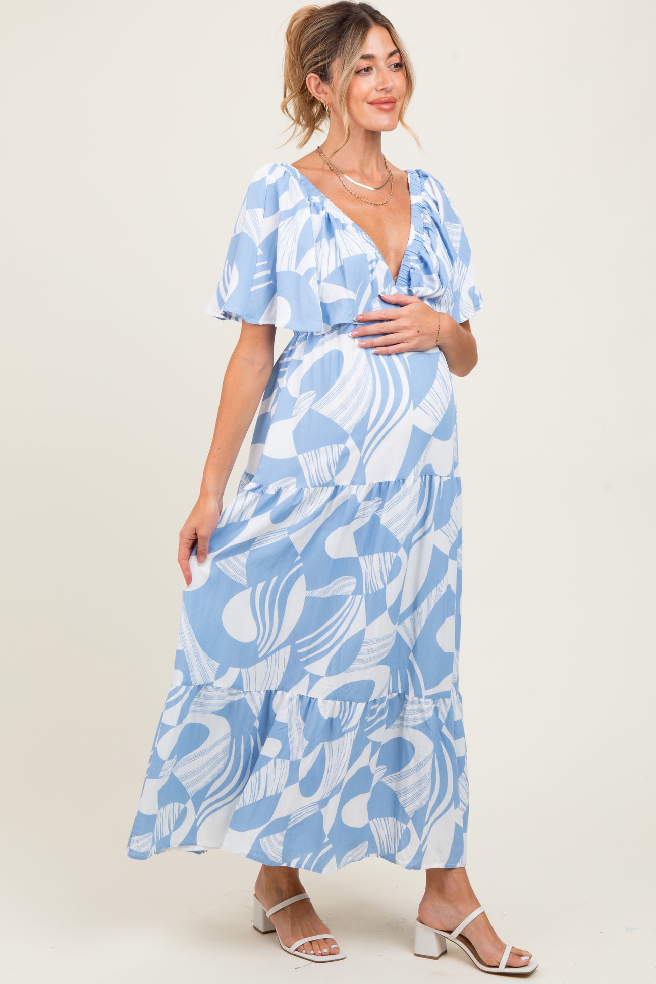 woman wearing a blue and white patterned maternity maxi dress with ruffled sleeves and a visible baby bump