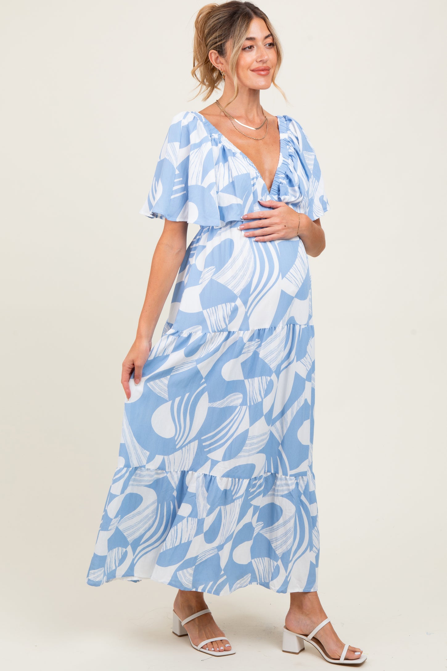 woman wearing a blue and white patterned maternity maxi dress with ruffled sleeves and a visible baby bump