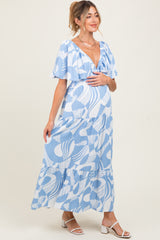 woman wearing a blue and white patterned maternity maxi dress with ruffled sleeves and a visible baby bump
