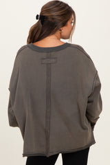 woman wearing a loose-fitting dark gray maternity sweatshirt with distressed details and a relaxed silhouette