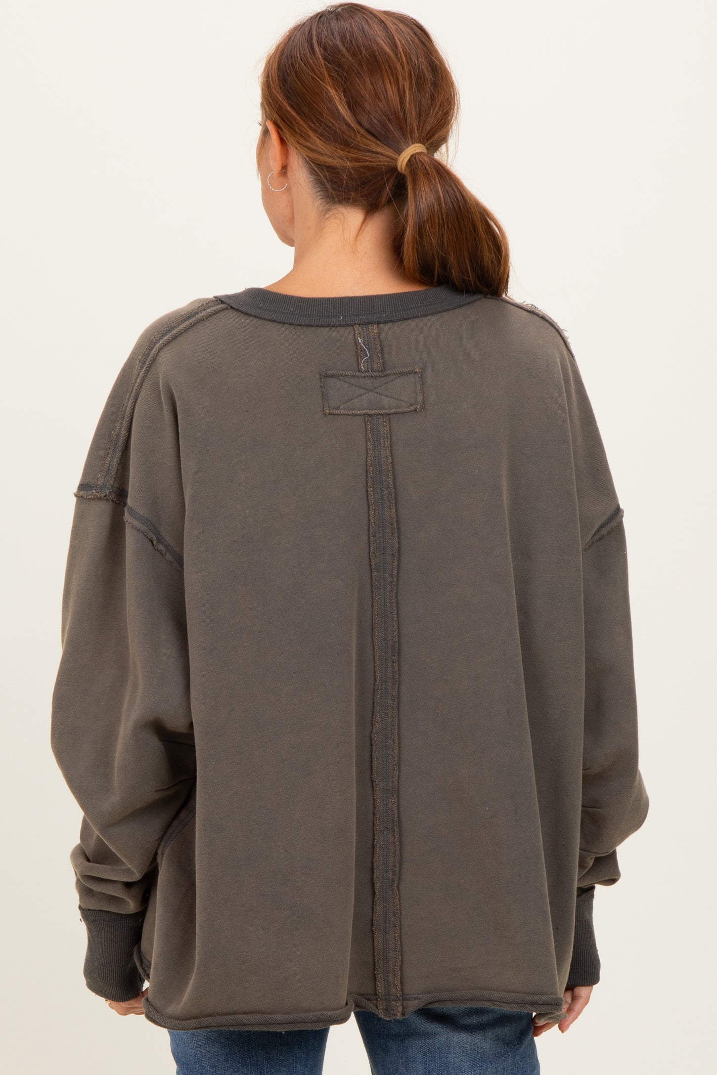 woman wearing an oversized charcoal gray fleece sweatshirt with a back seam detail