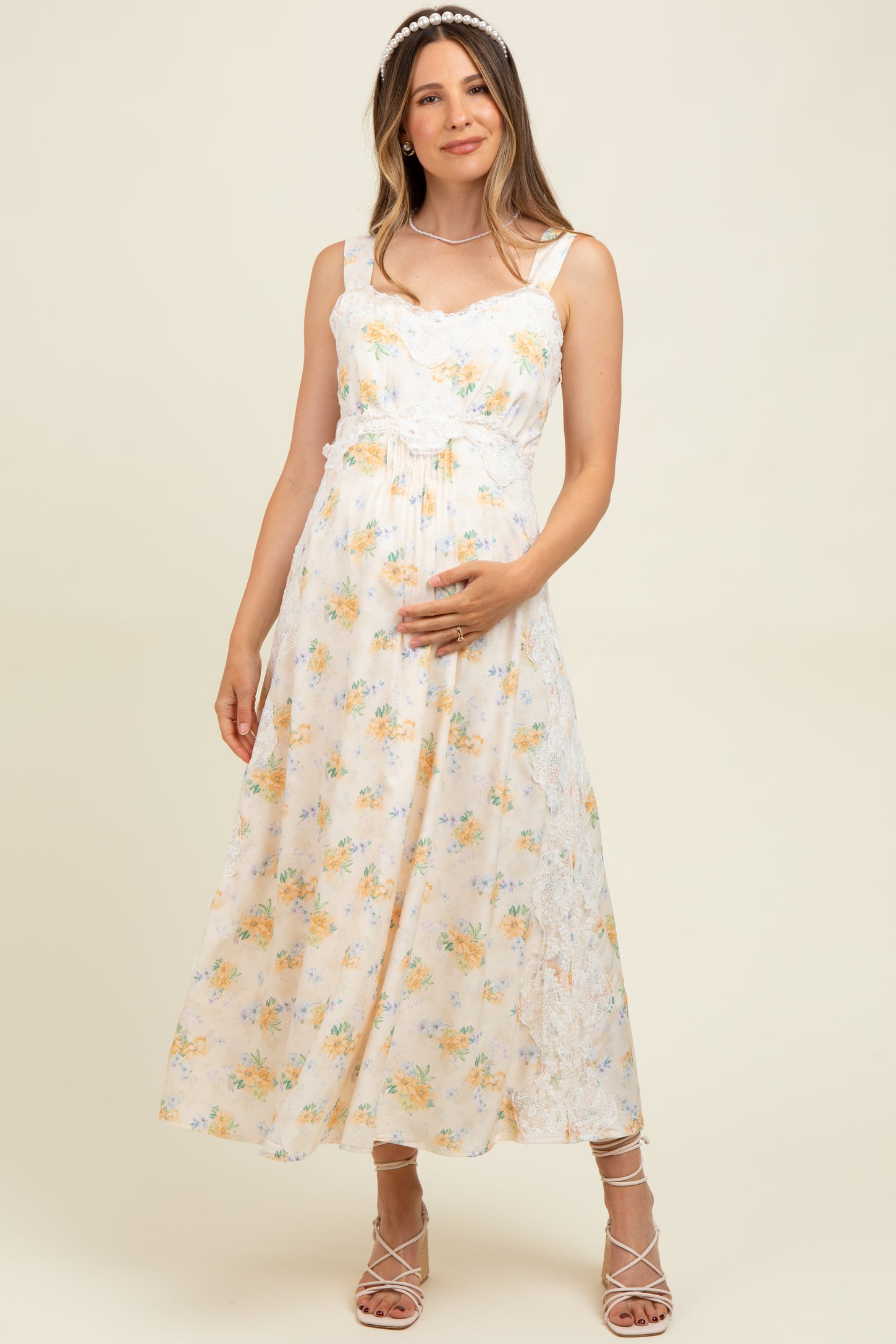 woman wearing a floral print maternity maxi dress with lace details and holding her baby bump