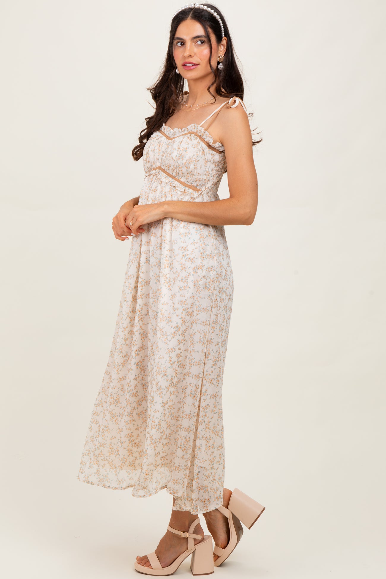 woman wearing a floral print maxi dress with spaghetti straps and a flowy silhouette, paired with beige block-heeled sandals