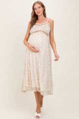 woman wearing a cream floral maternity maxi dress and holding her baby bump