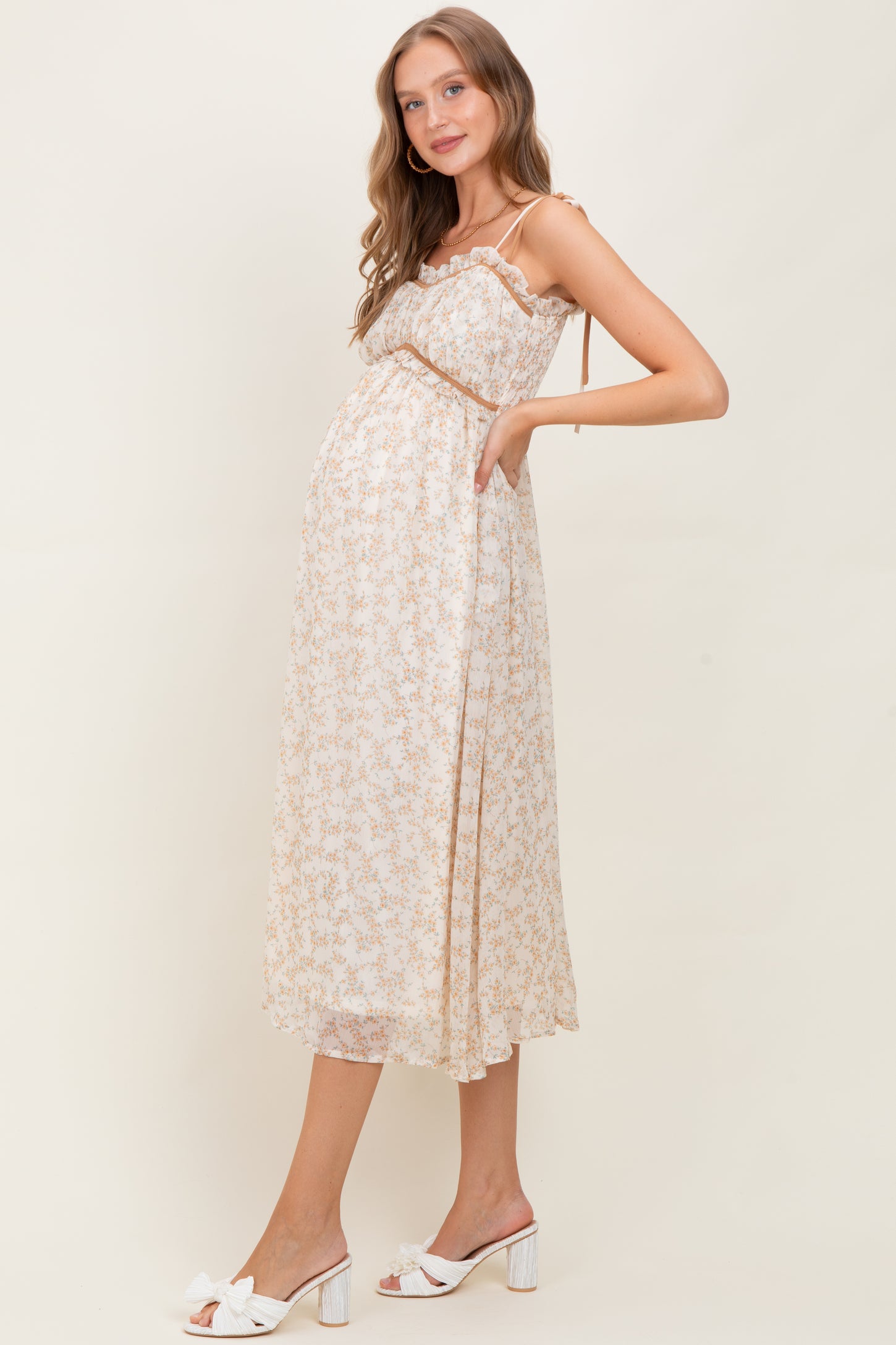 woman wearing a floral midi maternity dress with a ruffled bodice and a visible baby bump